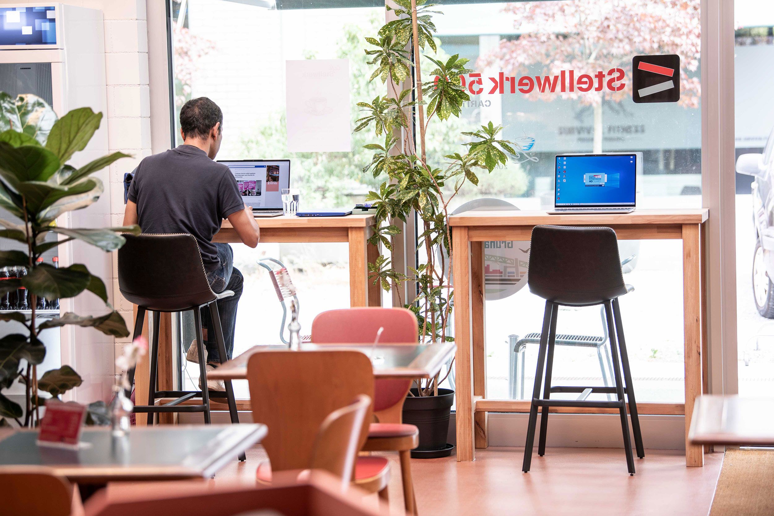 Eine Person sitzt an der Fensterbank in der Lernstube und lernt am Laptop.