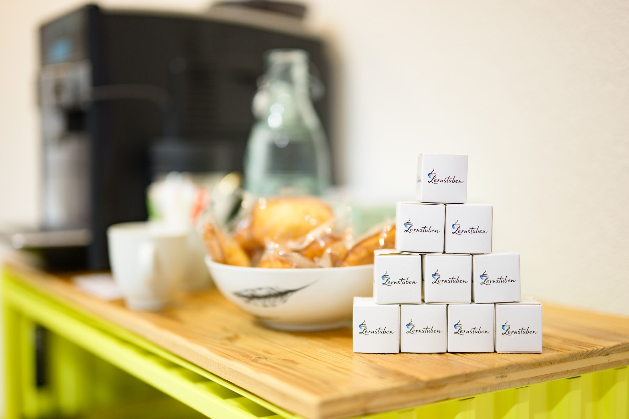 Kaffeeecke der Lernstube Kloten verschwommen im Hintergrund. Vorne sieht man eine Pyramide mit Lernstuben-Traubenzückerli